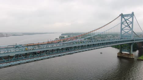 Aerial-dolly-shot-of-Ben-Franklin-Bridge-from-Philadelphia,-panorama-of-Camden-New-Jersey-NJ,-establishing-shot