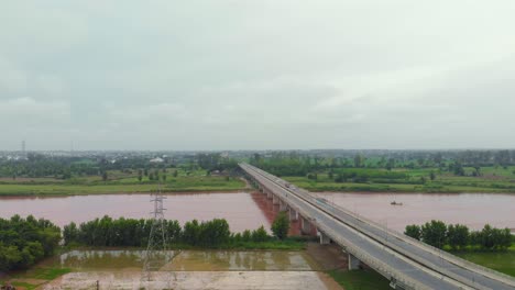 Luftaufnahme-Der-Überführung-über-Ackerland-In-Der-Nähe-Des-Flusses-Und-Des-Kanals-Nach-Regen-Mit-Regnerischem,-Schlammigem-Wasser-Außerhalb-Der-Stadt-In-Der-Region-Punjab,-Indien