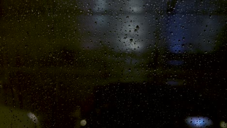 Cars-passing-in-front-of-a-window-full-of-raindrop-at-night