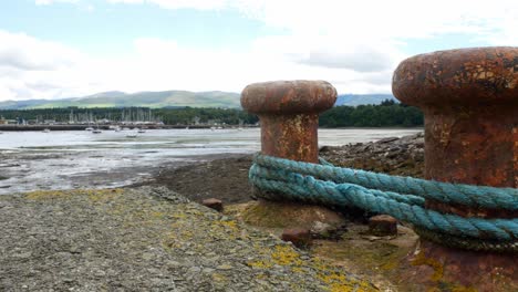 Rusty-metal-mooring-with-rope-overlooking-coastal-fishing-harbour-dolly-left