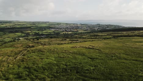 Slow-aerial-panning-shot-of-Irish-countryside-looking-down-to-town-and-ocean