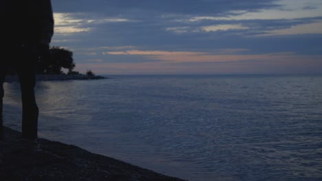 Man-Squatting-To-Take-Photo-Of-The-Ocean-During-A-Beautiful-Sunset---medium-shot