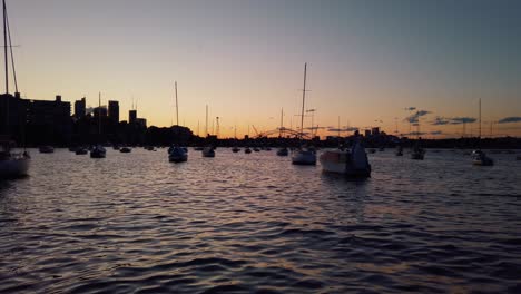Sonnenuntergang-In-Der-Bucht-Mit-Silhouette-Von-Segelbootmasten-Und-Hafenbrücke-In-Der-Ferne