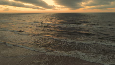 Sundown-aerial-view-of-waves-breaking-on-shore,-dramatic-seascape,-drone-shot