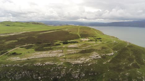 Aerial-view-rising-above-Great-Orme-Llandudno-mountain-valley-rural-landscape-pull-back