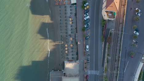 Toma-De-Drones-De-Arriba-Hacia-Abajo-De-La-Playa-Y-La-Carretera-De-Laigueglia,-Liguria-Durante-La-Puesta-De-Sol