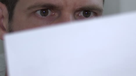 Close-shot-of-male-eyes-reading-and-reacting-to-shocking-paper-document