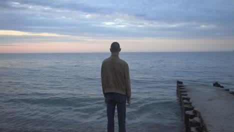 A-Young-Man-Standing-At-The-Shore-While-Watching-The-Beach-During-Sunset---Wide-Shot