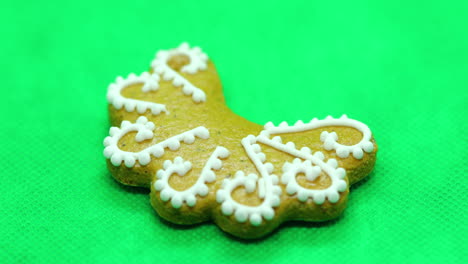 Zoomed-in-a-gingerbread-pastry-with-white-decorations-on-top-in-the-shape-of-a-Christmas-moon-on-a-green-background