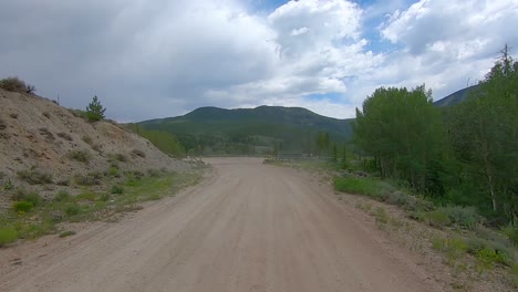 POV-thru-the-rear-window-while-driving-up-a-narrow-gravel-road-in-mountain-pass-in-the-Rocky-Mountains-of-Colorado-USA