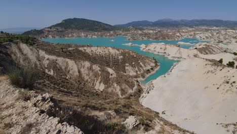 Tilting-Upshot,-Scenic-view-of-the-Barrancos-de-Gebas---La-Muela-Lake-in-Sierra-Espuna,-Mountain-range-in-the-background