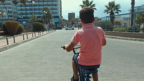 Kleiner-Junge-Mit-Seinem-Fahrrad-Entlang-Des-Piers-Auf-Einem-Sonnigen-Ausflug-Gimbal-Follow-Shot