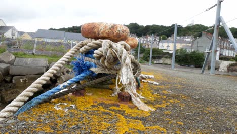 Ropes-tied-to-rusty-metal-mooring-on-coastal-marine-fishing-harbour-shipyard-dolly-left