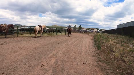 Cowboys-ride-and-walk-along-a-dirt-road-in-the-rodeo-grounds-in-Northern-Arizona