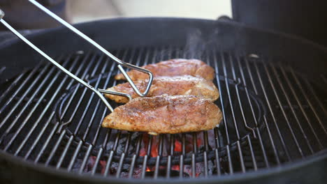 Turning-or-flipping-spiced-chicken-breasts-grilling-on-the-barbecue---slow-motion