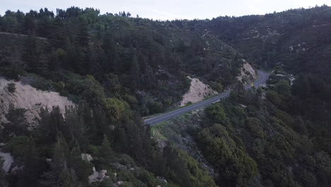 Scenic-road-through-California-mountains-at-dusk,-aerial-view