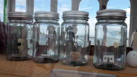 Glass-jars-filled-with-important-life-choices-wooden-models-dolly-left