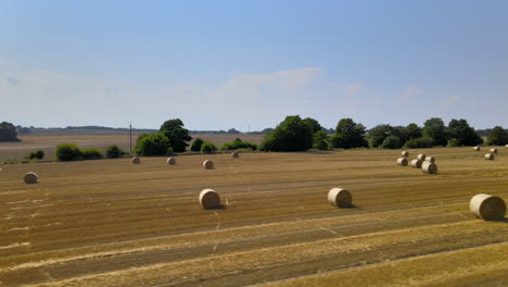 Golden-hay-field-with-round-hay-bales-aerial-truck-shot-of-flat-rural-farmland