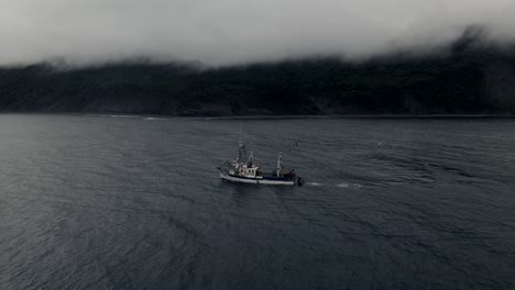 Barco-De-Pesca-Navegando-En-El-Golfo-De-San-Lorenzo-Con-Montañas-Costeras-En-El-Fondo-Cubiertas-De-Una-Espesa-Niebla-En-Quebec,-Canadá