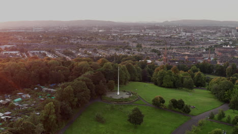 A-revolving-drone-shot-of-the-flag-pole-at-the-top-of-Queen's-Park,-Glasgow