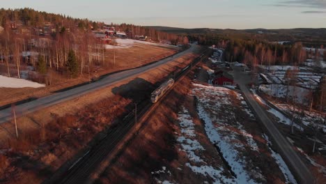 Train-passes-countryside,-End-of-winter,-Snow-is-melting,-Aerial-forward