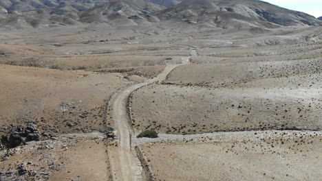Road-crossing-arid-desert-of-Morocco-with-mountains-in-background