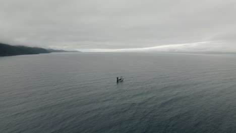 Lone-Fishing-Boat-Floating-At-The-Middle-Of-The-Open-Sea-On-A-Gloomy-Day---Drone-Shot