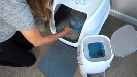 Woman-cleaning-a-cat-litter-box-by-scooping-litter-clumps-and-adding-fresh-litter