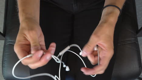 Top-view-of-hands-successfully-untangling-white-in-ear-headphones