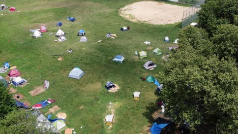 Aerial-of-tents-pitched-in-public-park,-outdoor-urban-camping-on-baseball-field-diamond,-roughing-it-outside-recreation-concept