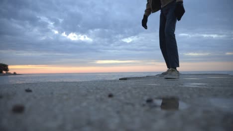 Man's-Feet-Wearing-Shoes-Walking-Along-The-Sandy-Beach-With-Cloudy-Sky-Background---Low-Level-Shot