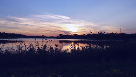 Sunset-on-the-lake,-early-evening-with-foliage-in-foreground,-no-persons