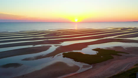 Cape-Cod-Bay-Epischer-Sonnenuntergang-Luftdrohnenaufnahmen-Eines-Stillen-Strandes-Bei-Ebbe-Mit-Hohem-Grünem-Gras,-Sandbänken-Und-Pfützen