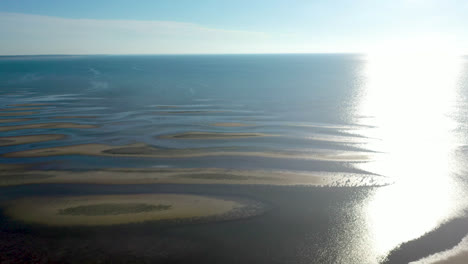 Cape-Cod-Bay-Aerial-Drone-Footage-of-Bay-Side-Beach-at-Low-Tide-with-Sand-Dunes-and-Sun-Panning-Shot