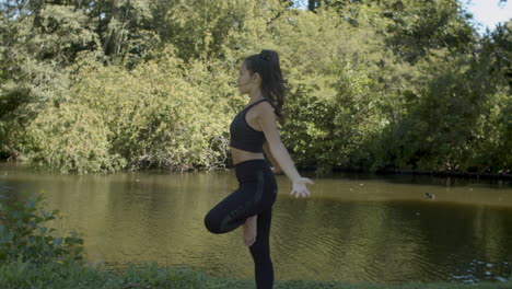 Young-woman-doing-sun-pose-and-namaste-greet-near-pond