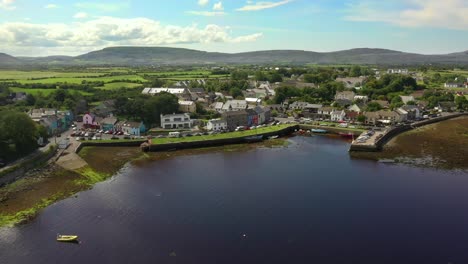 Kinvara,-Galway,-Ireland,-August-2020,-Drone-pulling-backwards-away-from-fishing-village-and-out-over-water