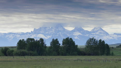 Snowy-Grand-Teton-mountains-of-Wyoming-seen-from-field-in-Idaho,-long-shot