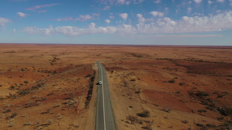 Aerial:-Drone-shot-following-a-white-4x4-vehicle-driving-down-an-empty-road-in-the-Australian-outback-near-Broken-Hill,-Australia