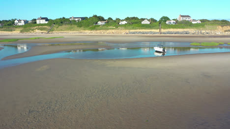 Cape-Cod-Bay-Aerial-Drone-Footage-of-Bay-Side-Beach-at-Low-Tide-Flying-Towards-Beach-Front-Houses-with-People-and-Beached-Boat