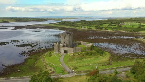 Dunguaire-Castle,-Kinvara,-Galway,-Ireland,-August-2020,-Drone-slowly-orbits-castle-passing-vista-of-Galway-Bay-revealing-Kinvara-Village-in-background