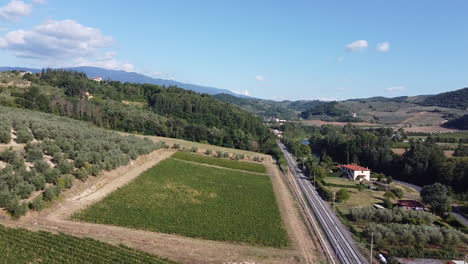 Italian-countryside-green-fields-and-vineyards-alongside-railway-tracks-on-sunny-quiet-day,-clear-blue-sky