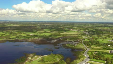 Dunguaire-Castle,-Kinvara,-Galway,-Ireland,-August-2020,-Drone-orbits-rural-landscape-revealing-view-of-Galway-Bay