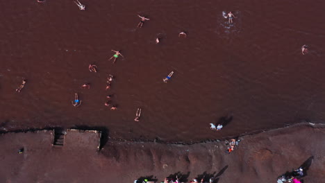 Aerial-top-down-shot-of-a-thalassotherapy-salt-lake-with-swimmers-floating-in-the-salty-brown-pond