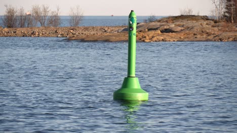 Green-navigation-buoy-floating-in-calm-sea-outside-umeå-harbour