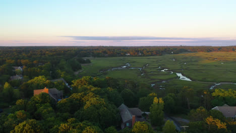 Cape-Cod-Bay-Aerial-Drone-Footage-of-Houses,-Marsh,-Tall-Green-Grass-and-Water-Creeks-at-Golden-Hour-Surrounded-by-Trees