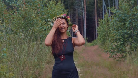 A-pretty-young-happy-girl,-smiling-and-walking-towards-camera-in-nature-during-an-outdoor-shoot-in-the-forest-between-trees-