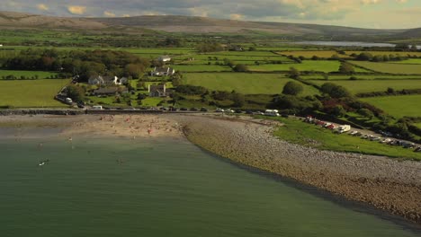 Flaggy-Shore,-Clare,-Ireland,-August-2020,-Drone-orbits-beach-with-Burren-landscape-in-the-background
