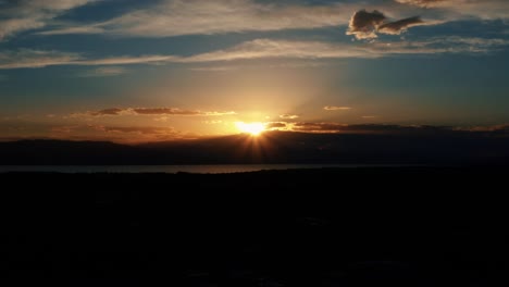 Atemberaubende-Luftdrohnenaufnahme-Eines-Wunderschönen-Orangefarbenen-Sonnenuntergangs,-Der-Unter-Einem-Berg-Am-Utah-Lake-Im-Utah-Valley,-USA,-Eintaucht