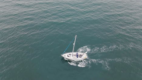 Reversing-and-tilting-aerial-view-of-sailboat-out-at-sea