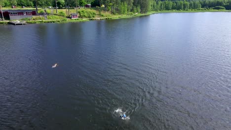 Professional-Swimmers-Racing-in-a-Wild-Lake,-Aerial-Reveal